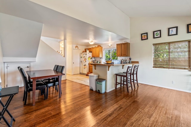 dining room with wood-type flooring and vaulted ceiling