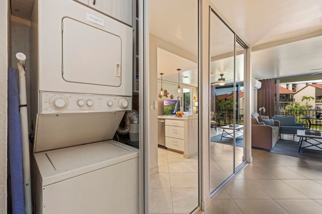 washroom with light tile patterned floors, stacked washer / dryer, and ceiling fan