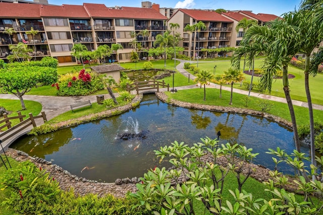 view of community featuring a yard and a small pond