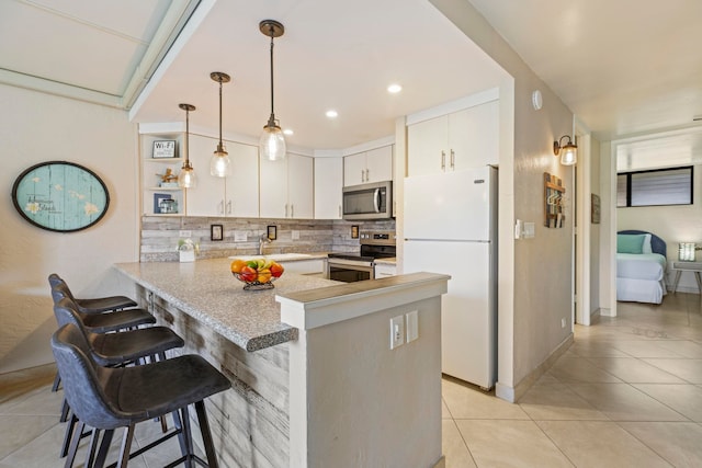 kitchen with backsplash, a kitchen breakfast bar, appliances with stainless steel finishes, decorative light fixtures, and kitchen peninsula