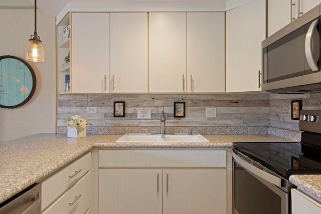 kitchen with sink, appliances with stainless steel finishes, tasteful backsplash, cream cabinetry, and decorative light fixtures