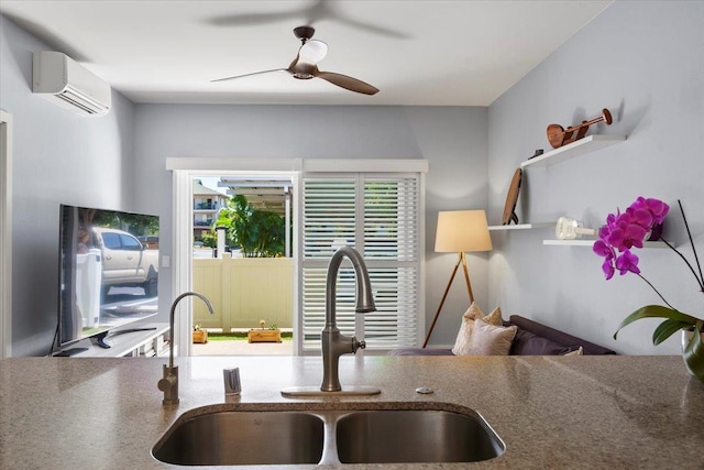 kitchen featuring a wall mounted AC, ceiling fan, stone counters, and a sink