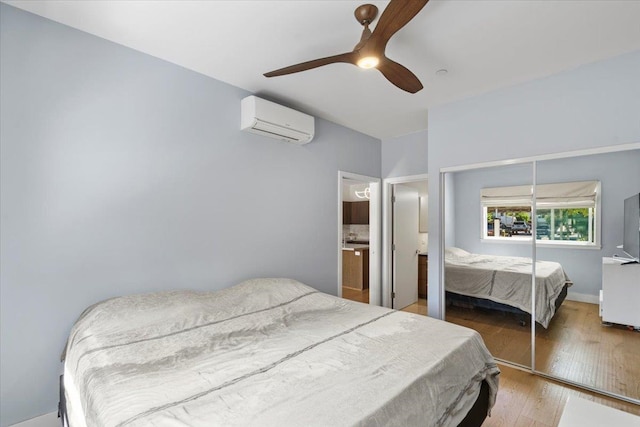 bedroom with ceiling fan, wood finished floors, a closet, and a wall mounted AC