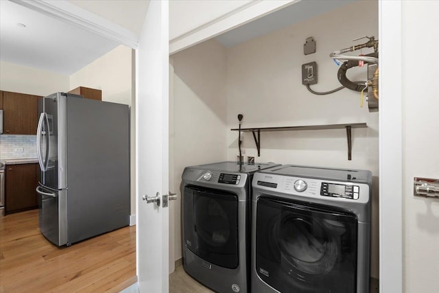 clothes washing area featuring light wood finished floors, laundry area, and washer and clothes dryer