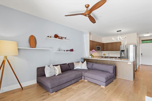 living room with light wood finished floors and ceiling fan with notable chandelier