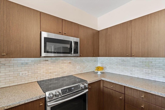 kitchen with light stone countertops, tasteful backsplash, and appliances with stainless steel finishes