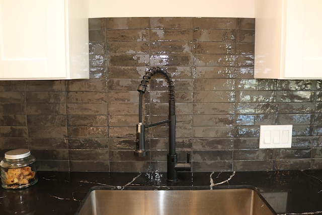 interior details featuring backsplash, white cabinetry, and a sink