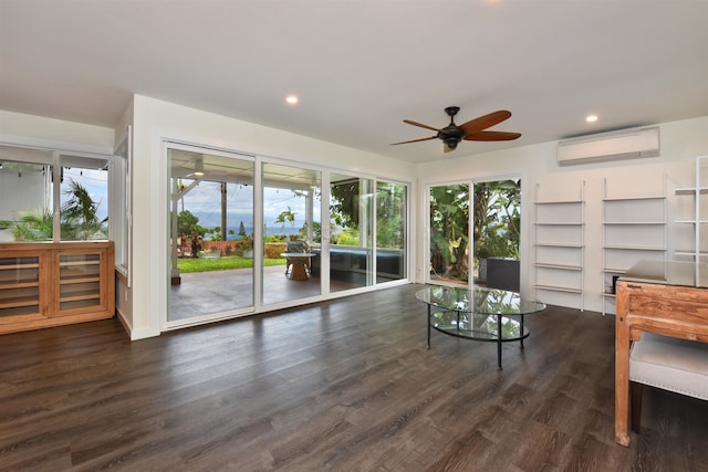 sitting room featuring dark wood-type flooring, an AC wall unit, and ceiling fan