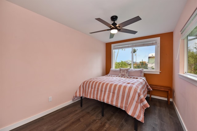 bedroom featuring ceiling fan, multiple windows, and dark hardwood / wood-style floors