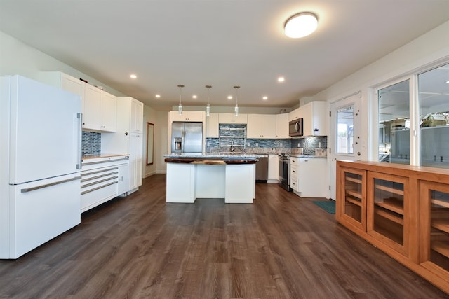 kitchen featuring stainless steel appliances, dark hardwood / wood-style flooring, a center island, white cabinets, and decorative light fixtures