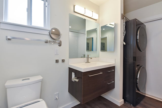 bathroom featuring hardwood / wood-style floors, vanity, toilet, and stacked washer and clothes dryer