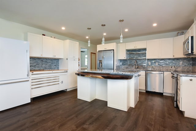 kitchen with backsplash, appliances with stainless steel finishes, dark hardwood / wood-style floors, and a center island