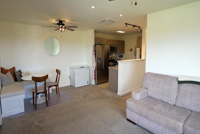 carpeted living room featuring track lighting and ceiling fan