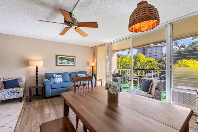 dining room featuring a textured ceiling, expansive windows, ceiling fan, and hardwood / wood-style flooring