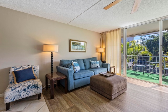 living room with a textured ceiling, hardwood / wood-style flooring, and ceiling fan