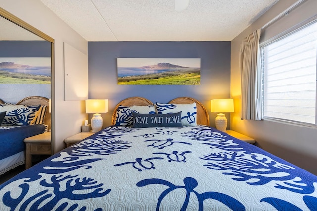 bedroom with a textured ceiling and multiple windows