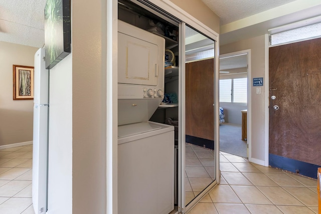 laundry room featuring light tile patterned floors and stacked washer / dryer