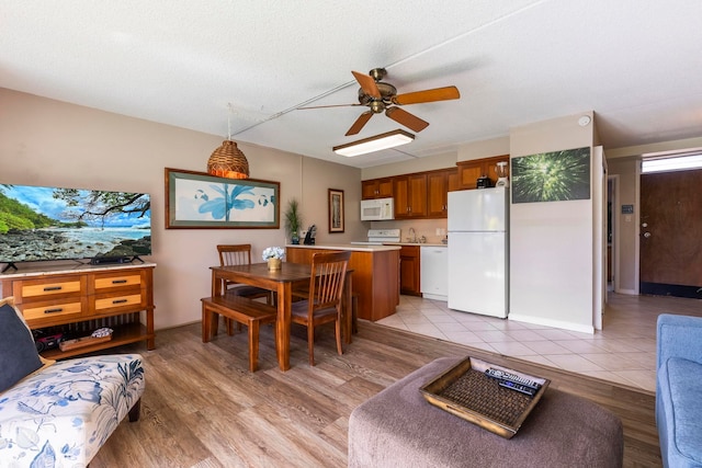 dining space featuring ceiling fan, light wood-type flooring, and a textured ceiling