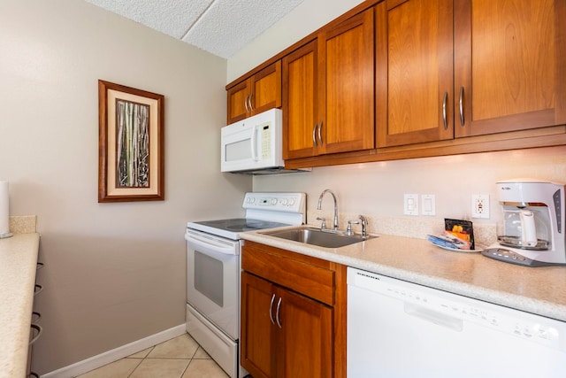 kitchen featuring light tile patterned flooring, white appliances, and sink