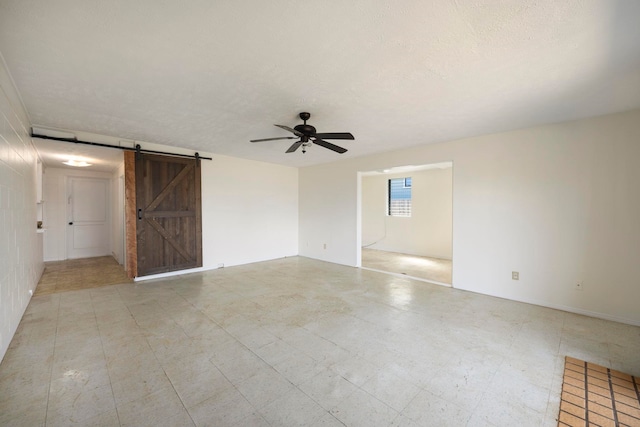 spare room with ceiling fan, a barn door, and a textured ceiling