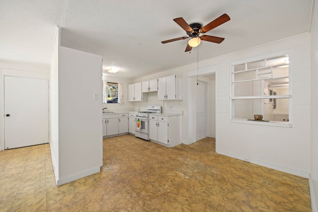 kitchen featuring sink, white gas range oven, ceiling fan, a textured ceiling, and white cabinetry