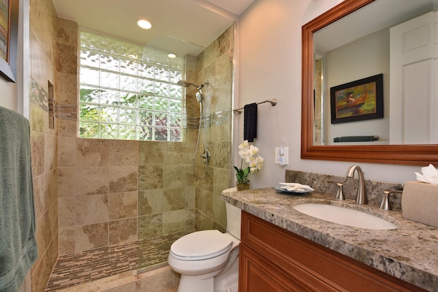 bathroom featuring vanity, toilet, and a tile shower