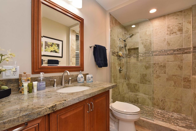 bathroom featuring vanity, toilet, and a tile shower