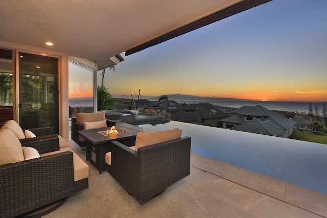 patio terrace at dusk featuring an outdoor living space with a fire pit and a water view