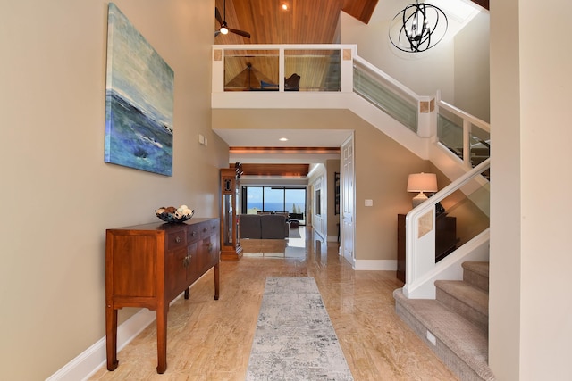 foyer with wood ceiling, a high ceiling, light wood-type flooring, and an inviting chandelier