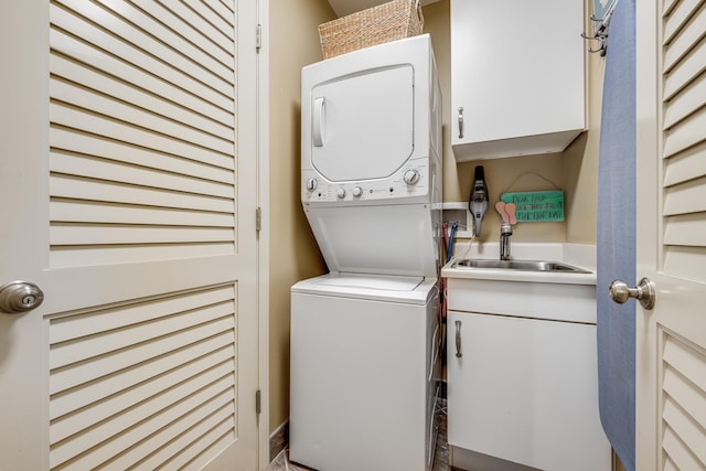 laundry room with cabinets, stacked washer / drying machine, and sink