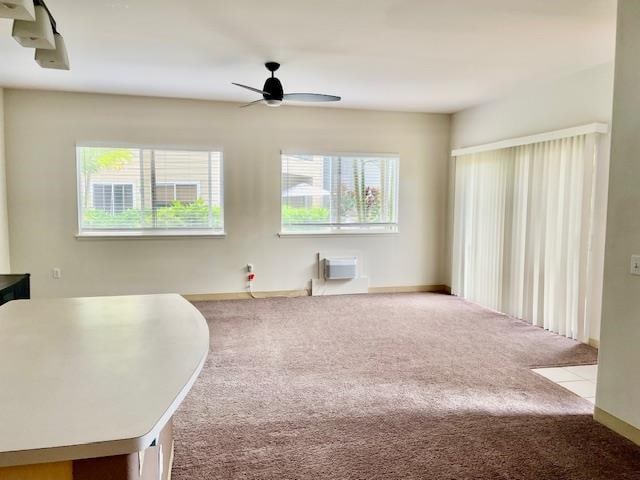 interior space with ceiling fan, a wall mounted AC, a wealth of natural light, and light carpet