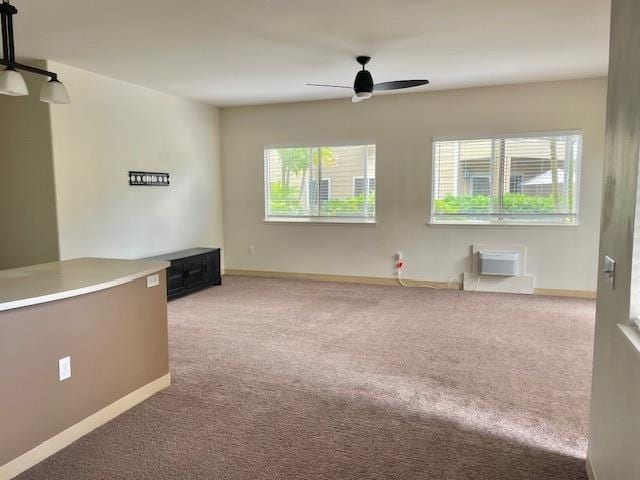 unfurnished room featuring an AC wall unit, ceiling fan, and carpet