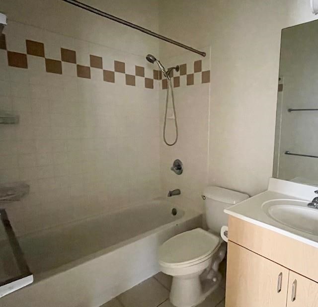 full bathroom with tile patterned flooring, tiled shower / bath combo, vanity, and toilet