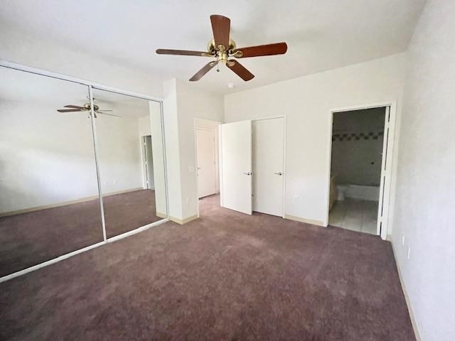 unfurnished bedroom with ceiling fan, a closet, and dark carpet