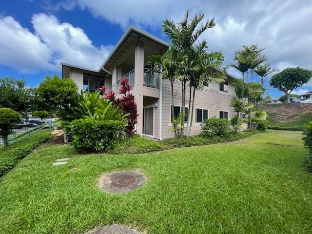 view of side of home featuring a balcony and a lawn