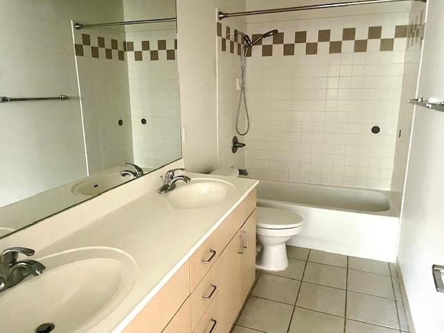 full bathroom with tiled shower / bath, tile patterned floors, vanity, and toilet