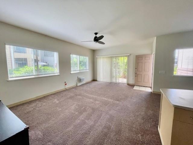 unfurnished living room featuring ceiling fan, a wealth of natural light, and carpet floors