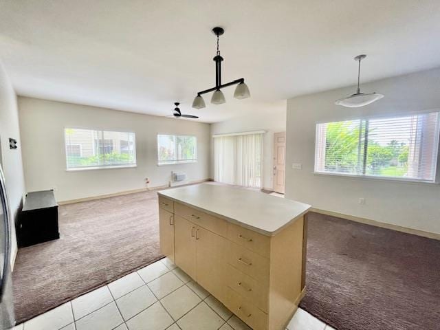 kitchen with ceiling fan, pendant lighting, light brown cabinetry, a center island, and light carpet