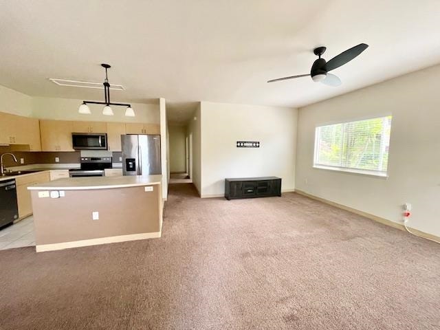 kitchen with light colored carpet, decorative light fixtures, sink, appliances with stainless steel finishes, and a center island