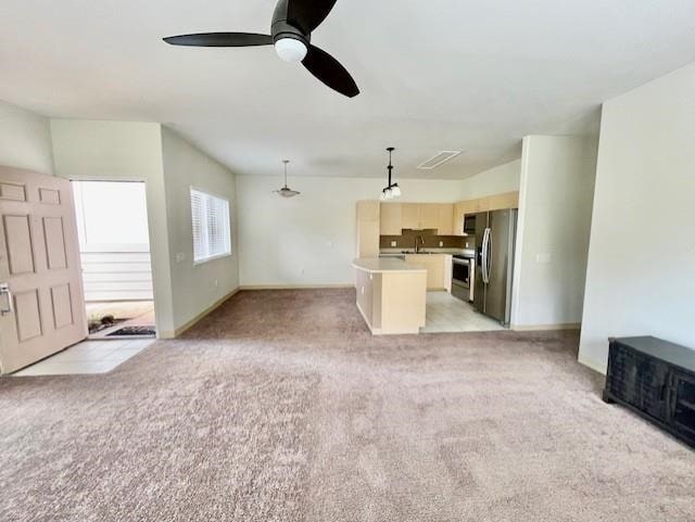 unfurnished living room featuring ceiling fan, sink, and light colored carpet