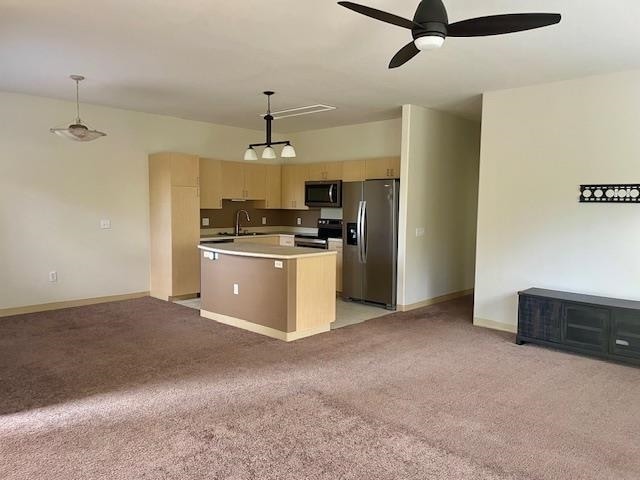 kitchen with light colored carpet, a center island with sink, sink, stainless steel appliances, and hanging light fixtures