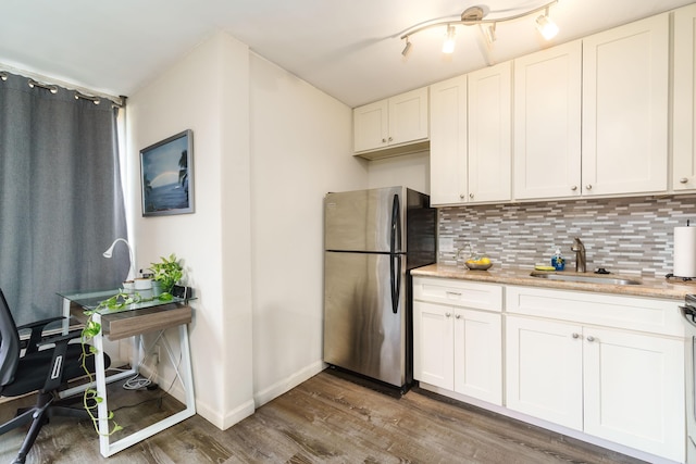 kitchen with decorative backsplash, stainless steel fridge, sink, wood-type flooring, and white cabinets