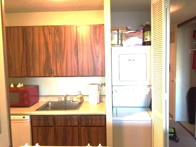 laundry area with stacked washer / dryer, sink, and a textured ceiling