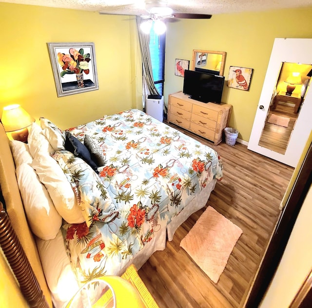 bedroom featuring hardwood / wood-style floors, a textured ceiling, and ceiling fan