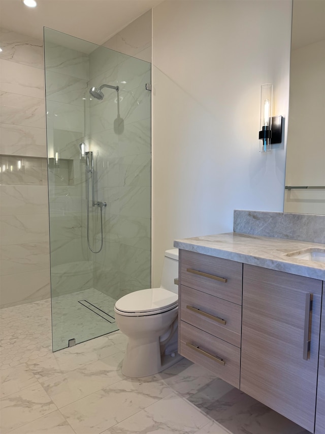 bathroom with tiled shower, vanity, and toilet