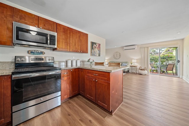 kitchen with a wall mounted air conditioner, light hardwood / wood-style flooring, kitchen peninsula, and appliances with stainless steel finishes