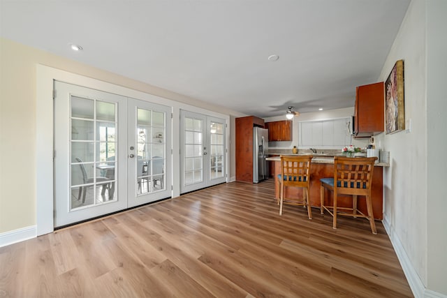 kitchen with ceiling fan, french doors, kitchen peninsula, wood-type flooring, and stainless steel fridge with ice dispenser