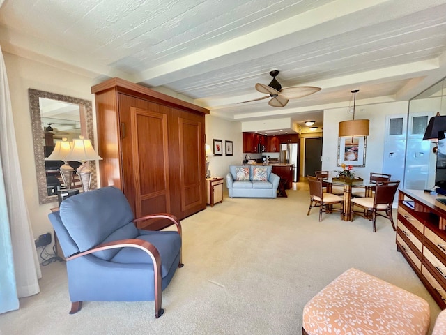 living room with ceiling fan, beamed ceiling, and light carpet