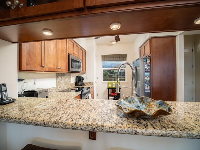 kitchen featuring kitchen peninsula, light stone countertops, and stainless steel appliances