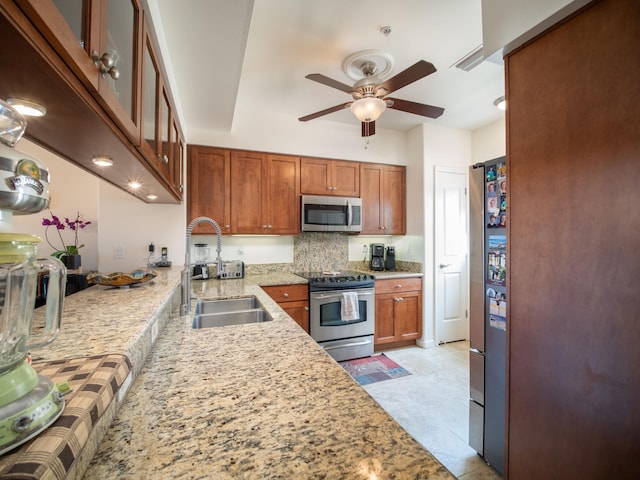 kitchen with light stone countertops, sink, ceiling fan, light tile patterned flooring, and appliances with stainless steel finishes